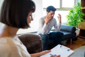 Close-up of a psychologist taking notes on clipboard during therapy session with her worried patient, psychotherapy boston