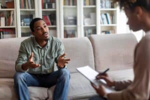 emotional-african-american-guy-attend-therapy-session-with-psychologist