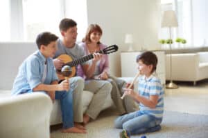 Portrait of handsome siblings and their father playing musical instruments at home, parenting education massachusetts