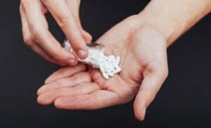 white-tablets-with-glass-jar-man-s-hand