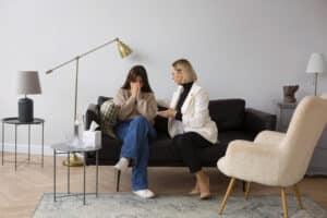 A girl sitting on a couch being consulted by a woman. Mental health evaluation Massachusetts
