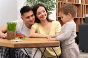Parents smiling proudly as their baby takes their first steps, parenting massachusetts