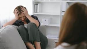 Sad young woman looking down, showing signs of distress and symptoms of PTSD