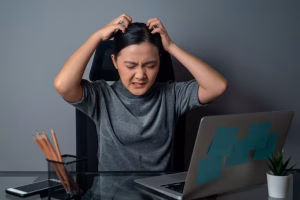 Woman looking annoyed and scratching her head in frustration, unable to focus or concentrate, difficulty concentrating MA