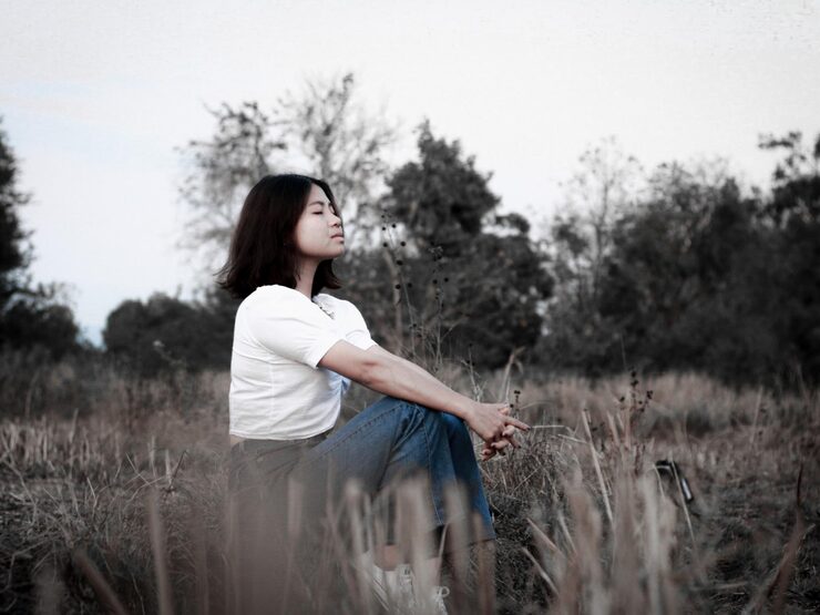 Woman sitting on the grass, appearing calm and peaceful as she heals from past trauma