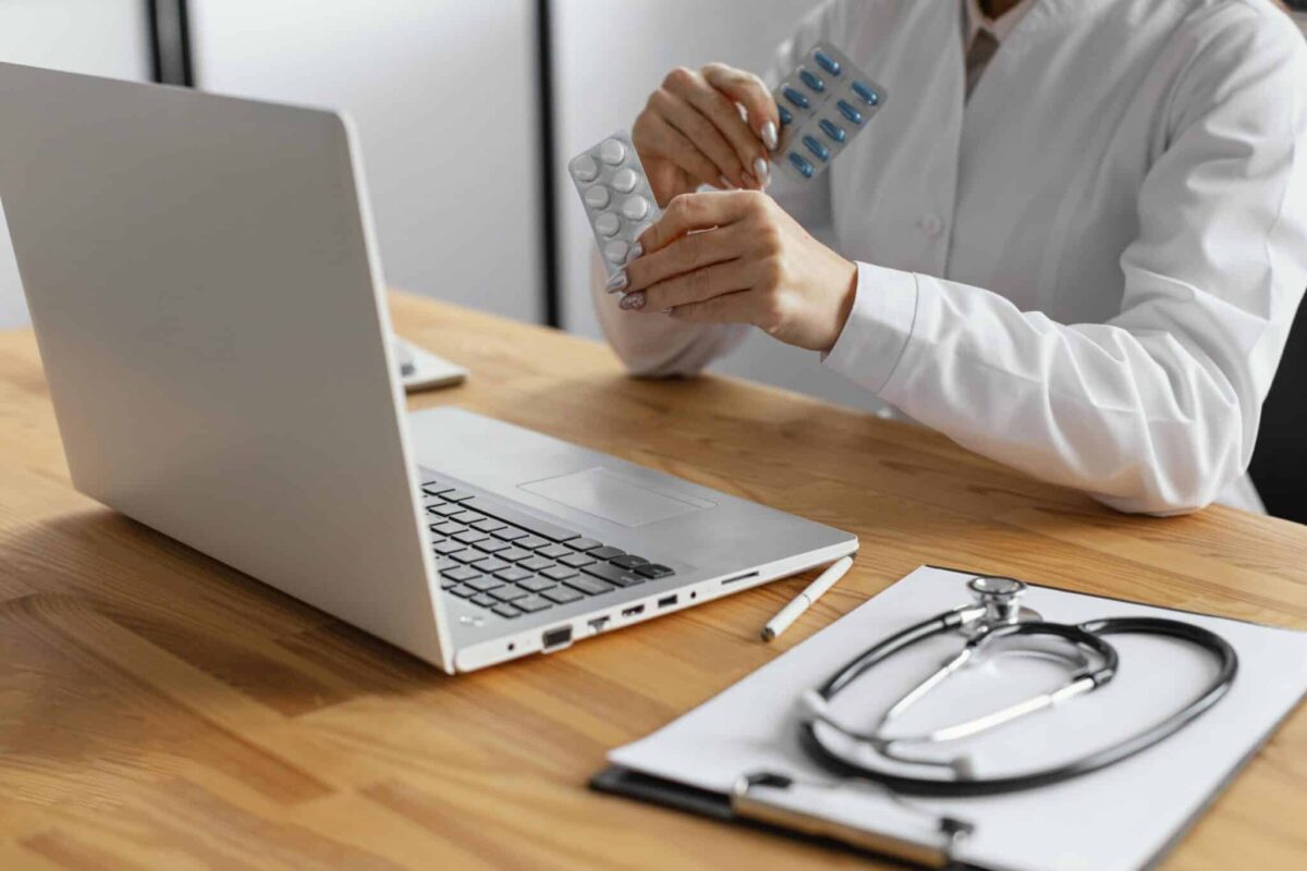 doctor holding pills while facing the laptop, online psychopharmacology massachusetts