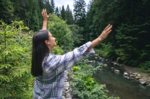 Happy young woman in a forest in a mountainous area enjoys nature near the river, DBT psychotherapy massachusetts