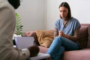 a person sitting on a couch having a therapy session with psychiatrist, combined treatment and medication massachusetts