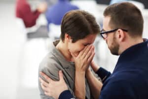 Helpful man reassuring upset woman at course of psychological support, pstd and trauma support massachusetts