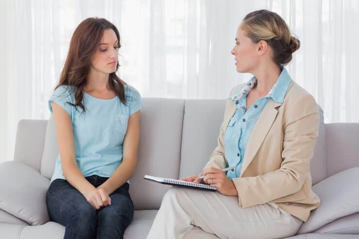 A woman talking with a psychiatrist in an office, illustrating What to Expect at Your First Psychiatry Appointment in Boston and the supportive atmosphere of mental health care.